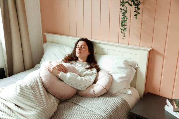 Женщина, лежащая в постели с поддерживающей подушкой в уютной палате.